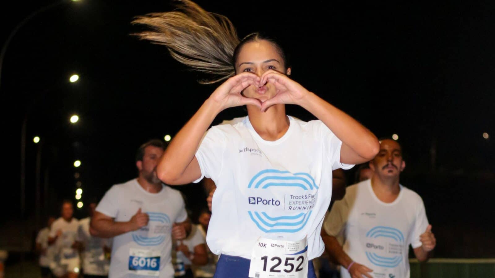 mulher correndo no percurso faz coração com as mãos corrida de rua méskle sports 1 night run track&field porto experience running indaiatuba março 2025